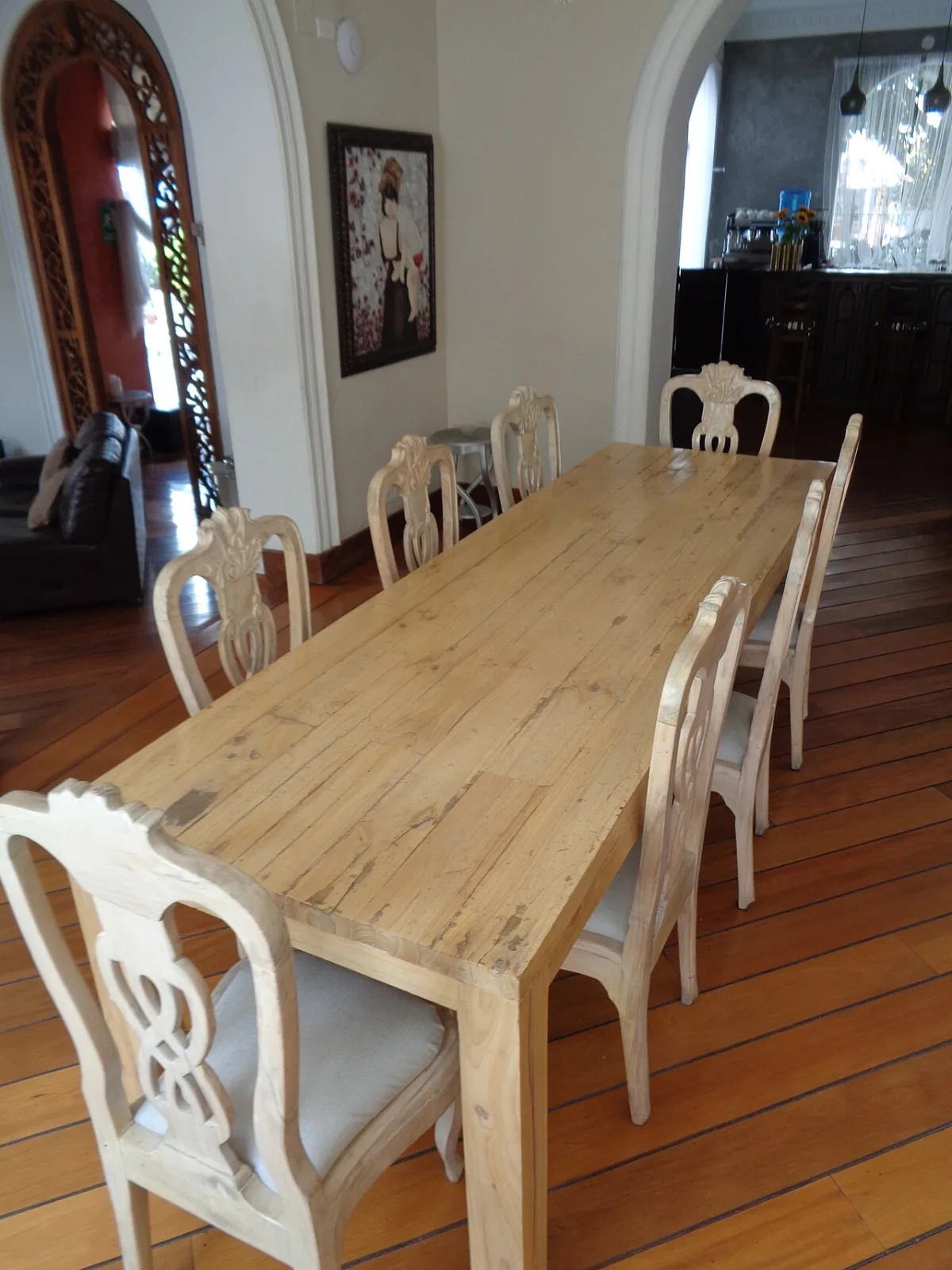 Lange houten eettafel met witte stoelen in een woonkamer