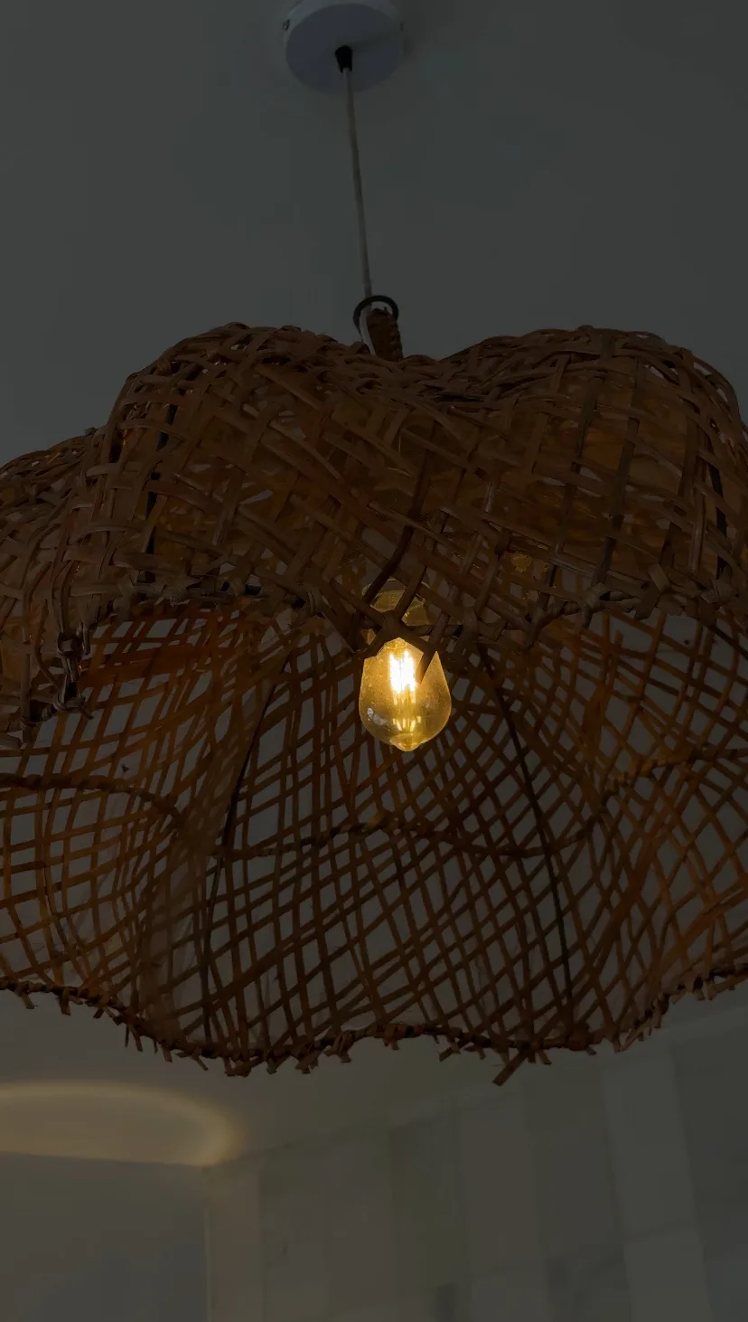Gevlochten rotan hanglamp met een brandende lamp erin
